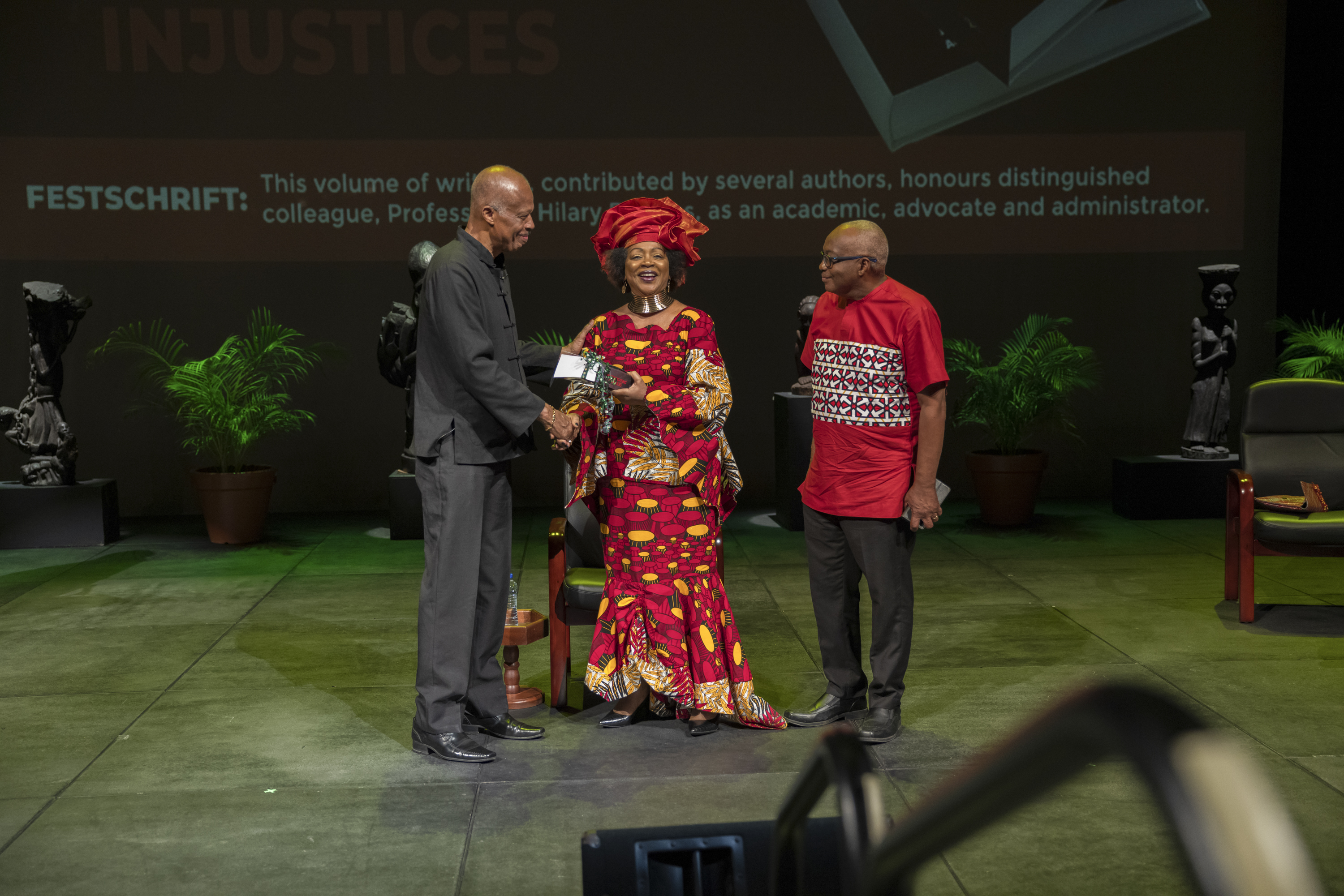 Professor Verene Shepherd (centre) and Dr. Henderson D. Carter (right), present a copy to Professor Sir Hilary Beckles.